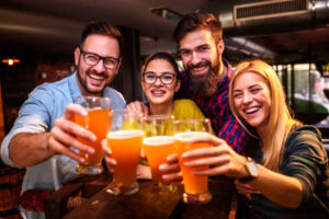 um grupo com quatro amigos em um bar brindando com cerveja