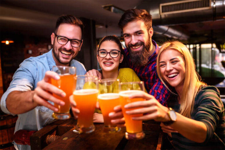 um grupo com quatro amigos em um bar brindando com cerveja