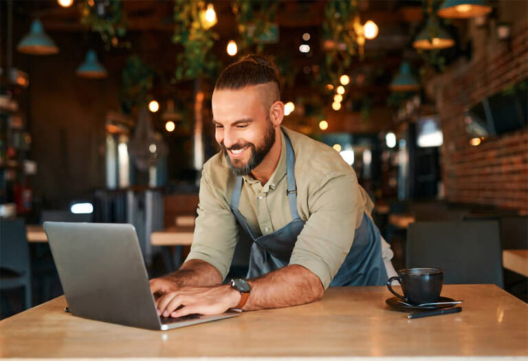 empreendedor digitando em um notebook que está em cima de uma mesa